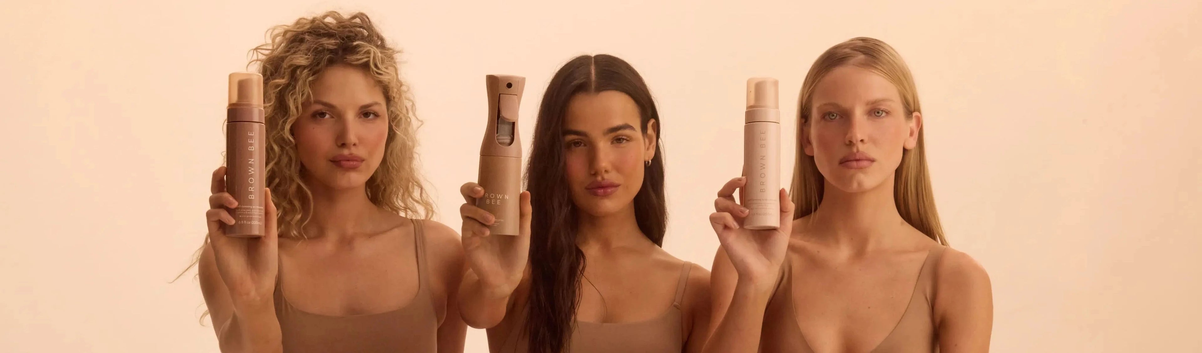 Three women holding brown bee products against a beige background